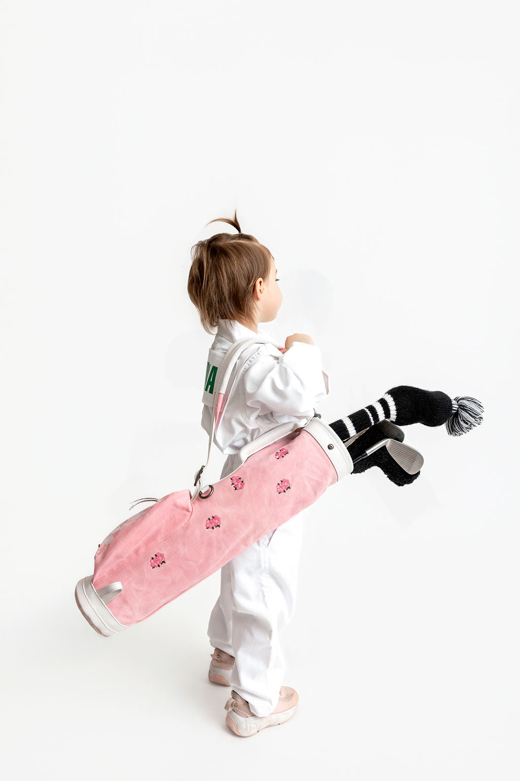 kid holding a pink junior golf bag with kids golf clubs inside